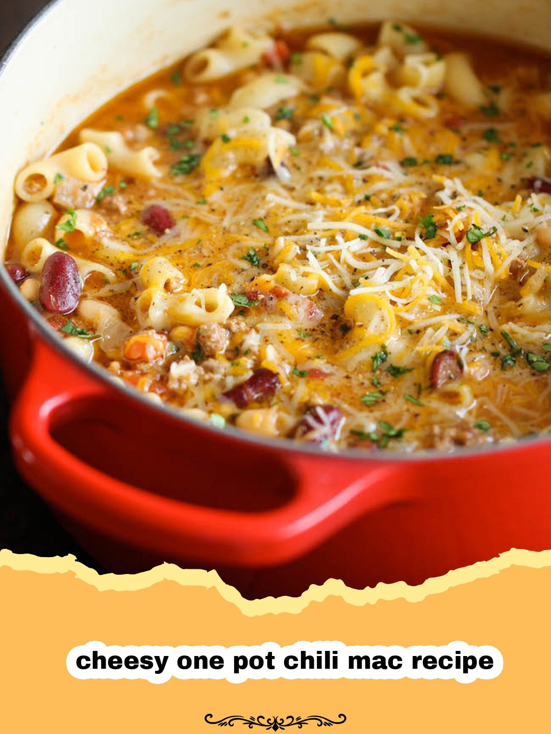 A large pot filled with bubbling, cheesy one pot chili mac, garnished with fresh green onions and a dollop of sour cream.