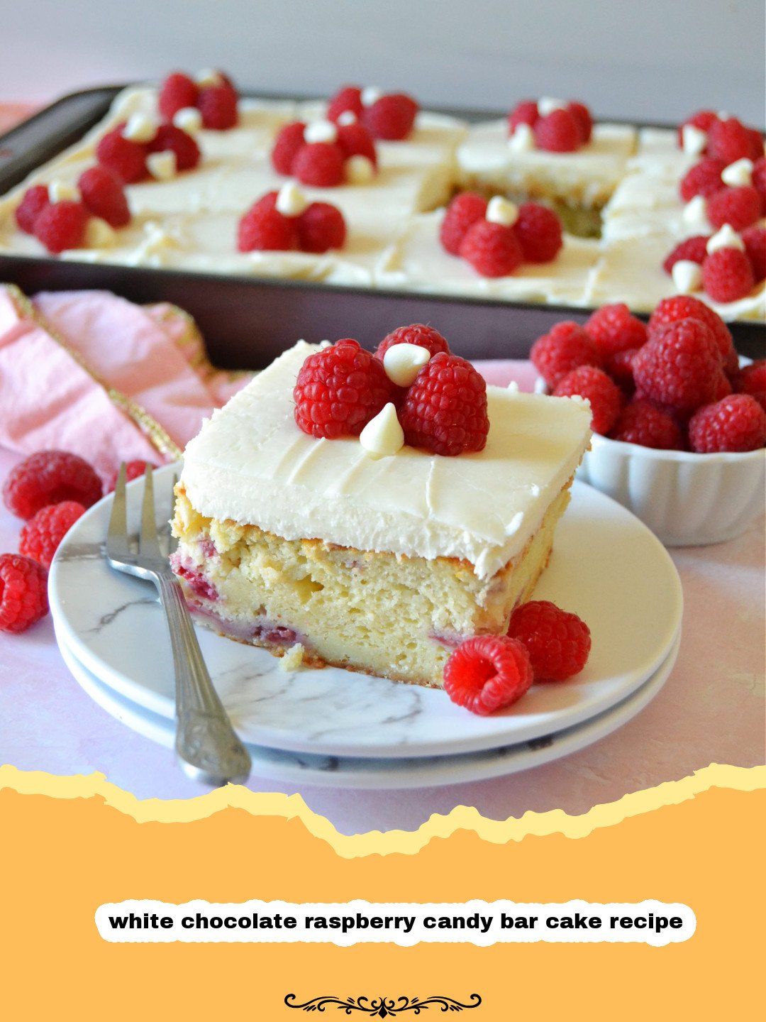 A beautifully decorated three-layer white chocolate raspberry candy bar cake with white chocolate frosting, raspberry filling visible, and fresh raspberries on top.