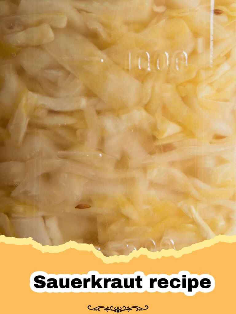 Close-up of a glass jar filled with golden, tangy homemade sauerkraut, with a few caraway seeds visible and fresh cabbage in the background.