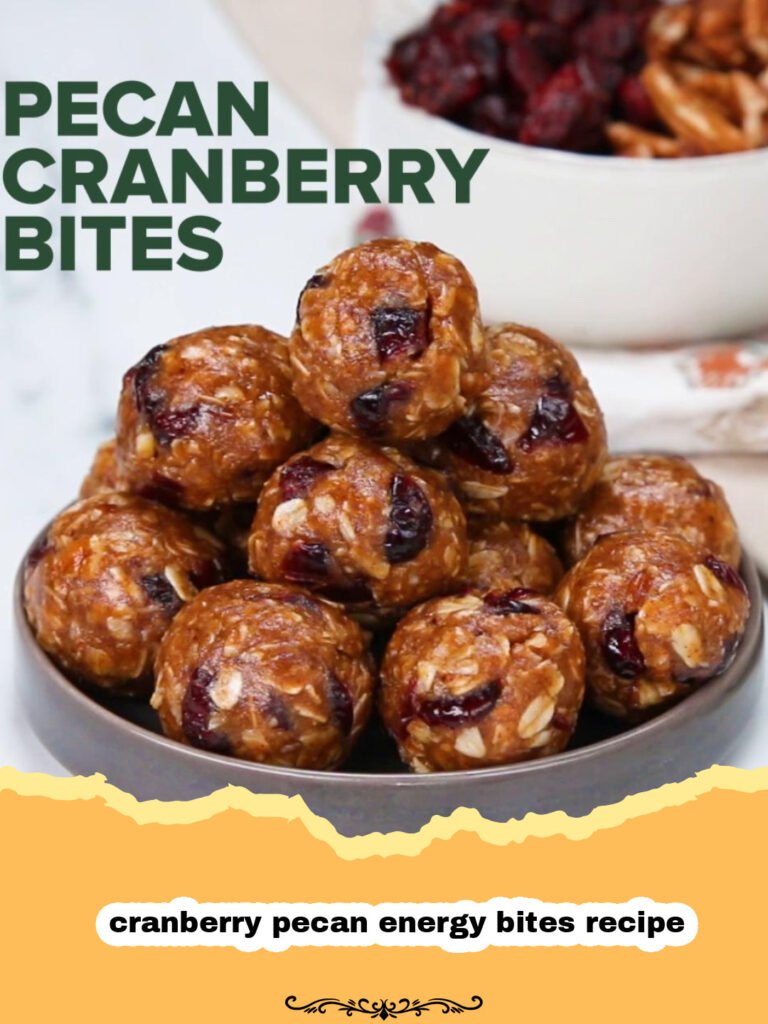 Pile of homemade cranberry pecan energy bites on a wooden board with scattered cranberries and pecans