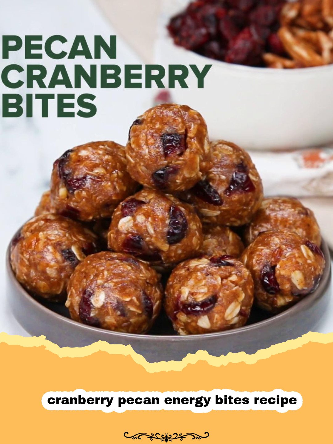 Pile of homemade cranberry pecan energy bites on a wooden board with scattered cranberries and pecans