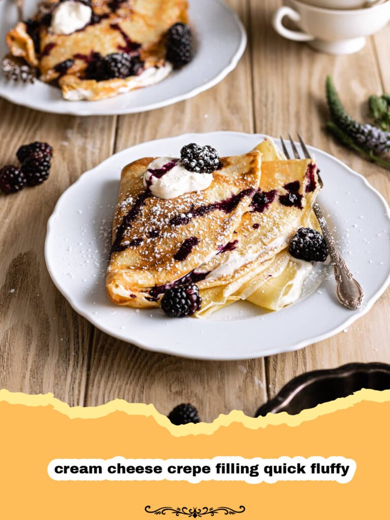 Close-up of fluffy cream cheese crepe filling being spread onto a crepe, with fresh berries in the background.
