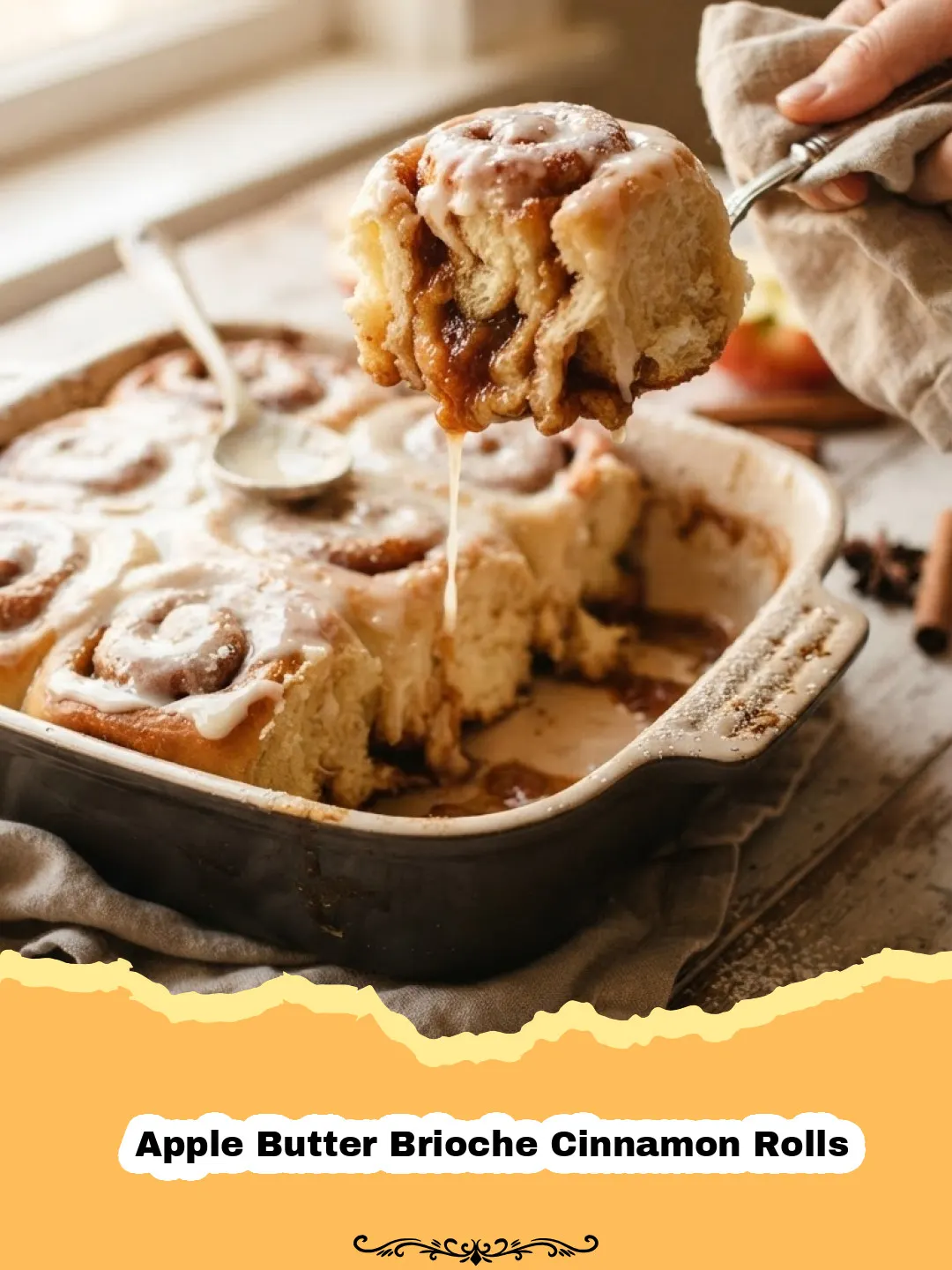 Close-up of golden brown Apple Butter Brioche Cinnamon Rolls drizzled with white glaze, resting in a baking dish.