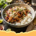 Peanut Chicken with Ginger Slaw & Coconut Rice - Plated Peanut Chicken with Ginger Slaw and Coconut Rice, garnished with peanuts and cilantro